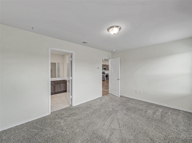 unfurnished bedroom with light carpet, ensuite bath, visible vents, and baseboards