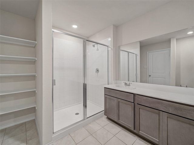 full bathroom featuring a stall shower, tile patterned flooring, baseboards, and vanity