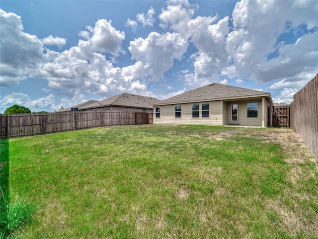 rear view of house with a yard and a fenced backyard