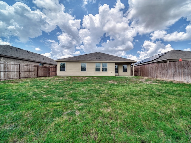 rear view of property with a yard and a fenced backyard