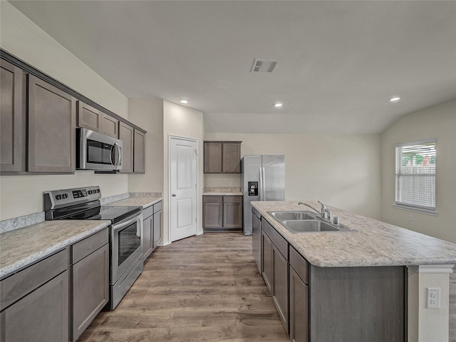 kitchen with a kitchen island with sink, light wood-style flooring, a sink, visible vents, and appliances with stainless steel finishes