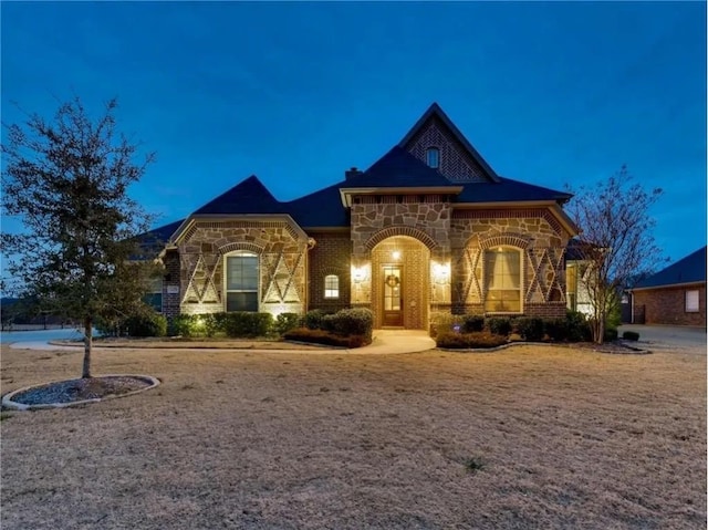 french country home featuring stone siding and brick siding