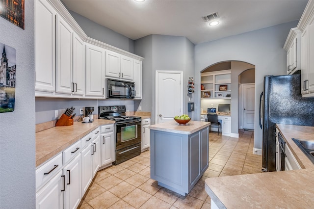 kitchen with arched walkways, light countertops, white cabinets, light tile patterned flooring, and black appliances