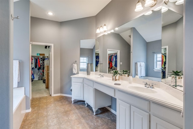 full bathroom with double vanity, a sink, a spacious closet, and a bath