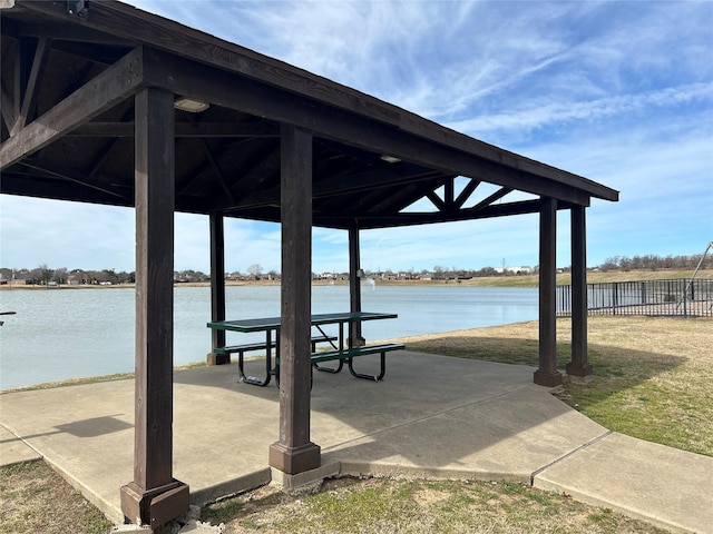 surrounding community with a water view, a patio area, fence, and a gazebo