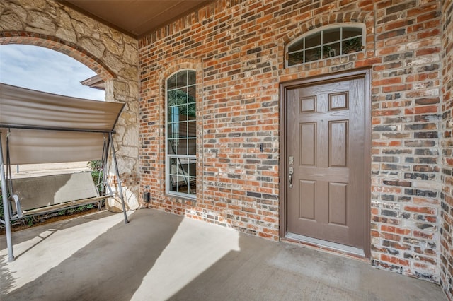 property entrance with a porch and brick siding