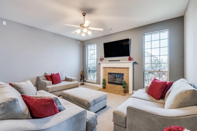 carpeted living room featuring a tile fireplace, ceiling fan, and baseboards