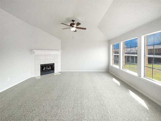 unfurnished living room featuring baseboards, a ceiling fan, a tile fireplace, lofted ceiling, and carpet