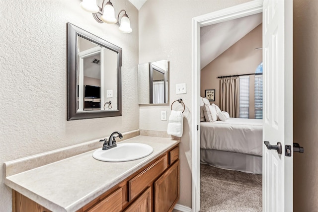 ensuite bathroom with lofted ceiling, ensuite bath, vanity, and a textured wall