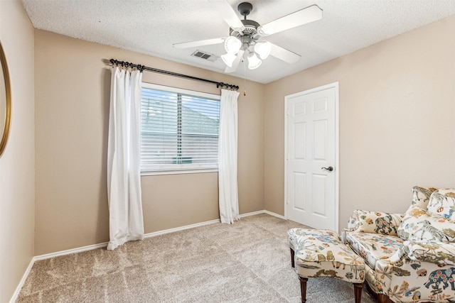 living area featuring carpet floors, ceiling fan, baseboards, and a textured ceiling