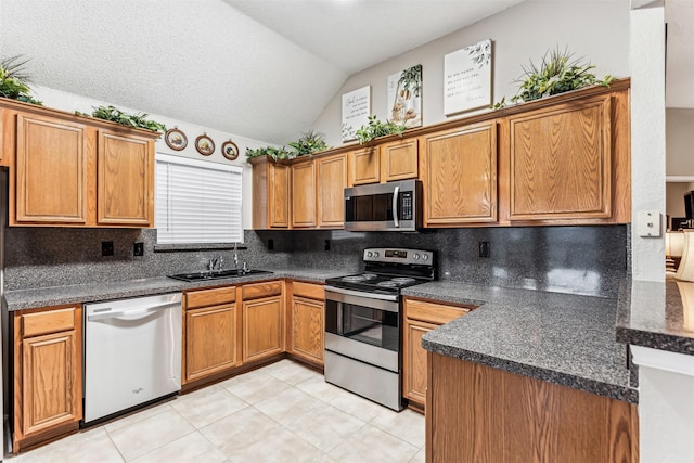 kitchen featuring stainless steel appliances, dark countertops, and brown cabinets