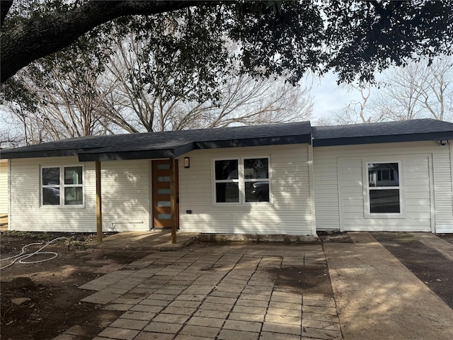 rear view of property featuring roof with shingles and a patio area