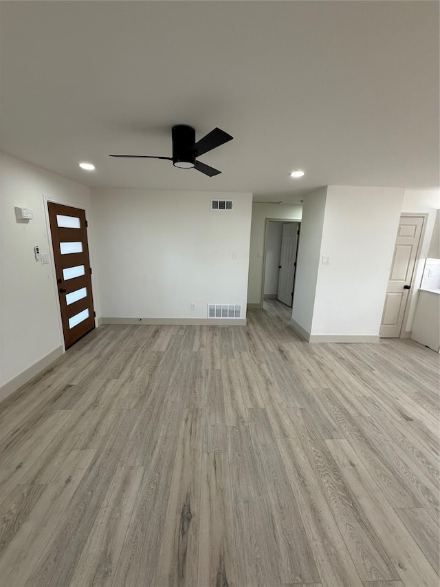 unfurnished room with a ceiling fan, light wood-type flooring, visible vents, and baseboards