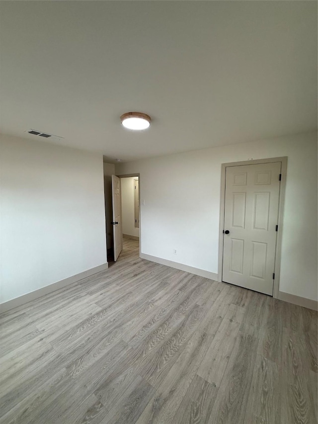 spare room featuring light wood finished floors and baseboards