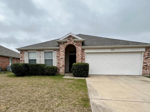 single story home with an attached garage, brick siding, a shingled roof, concrete driveway, and a front yard