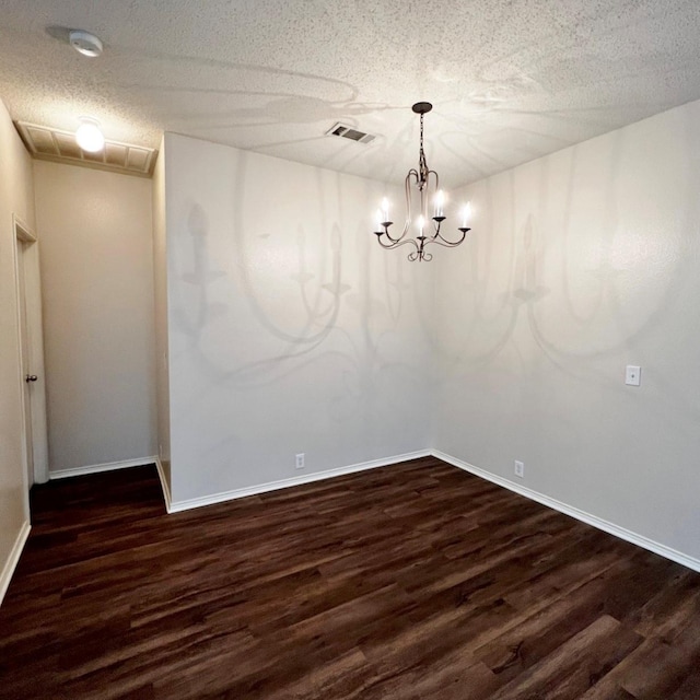 unfurnished dining area with a textured ceiling, visible vents, a chandelier, and dark wood-type flooring