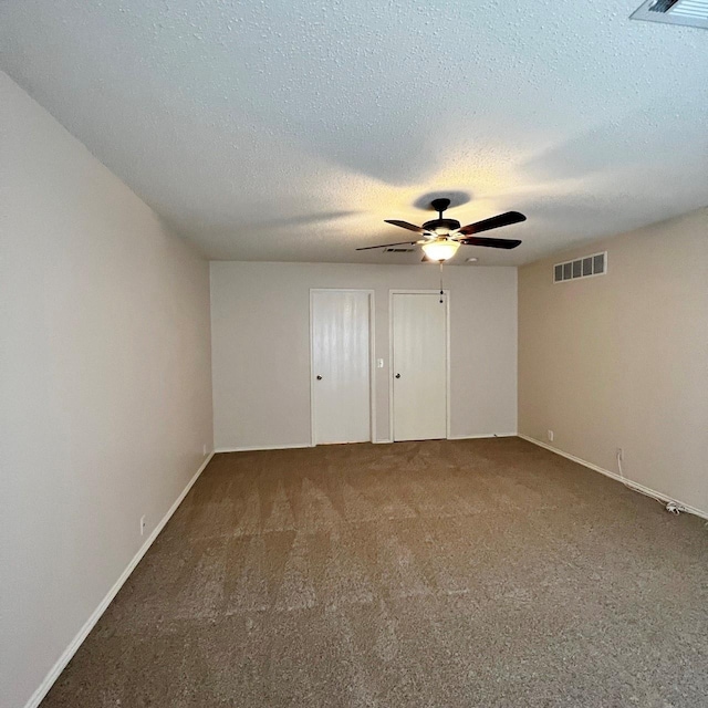 unfurnished room with carpet floors, ceiling fan, visible vents, and a textured ceiling