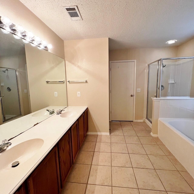 bathroom featuring a textured ceiling, tile patterned flooring, a sink, visible vents, and a stall shower