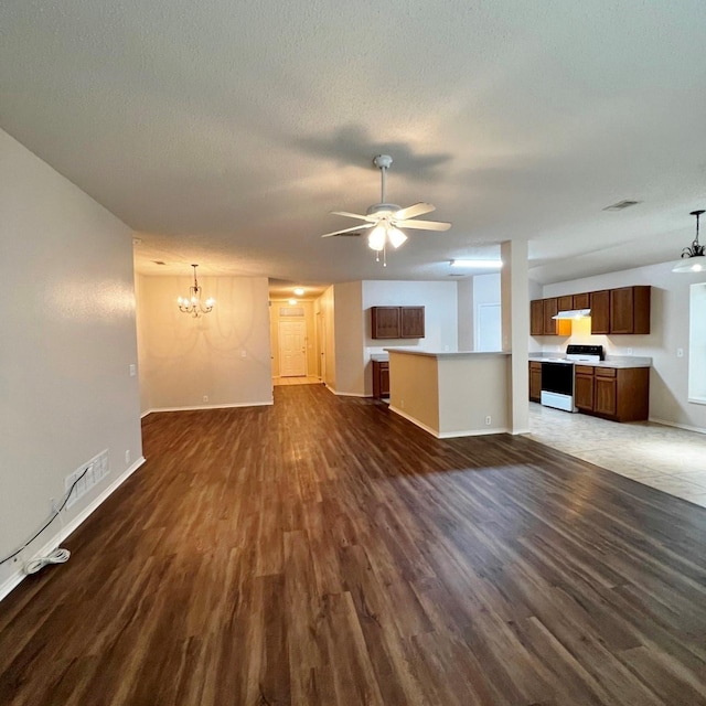 unfurnished living room with ceiling fan with notable chandelier, a textured ceiling, dark wood finished floors, and baseboards