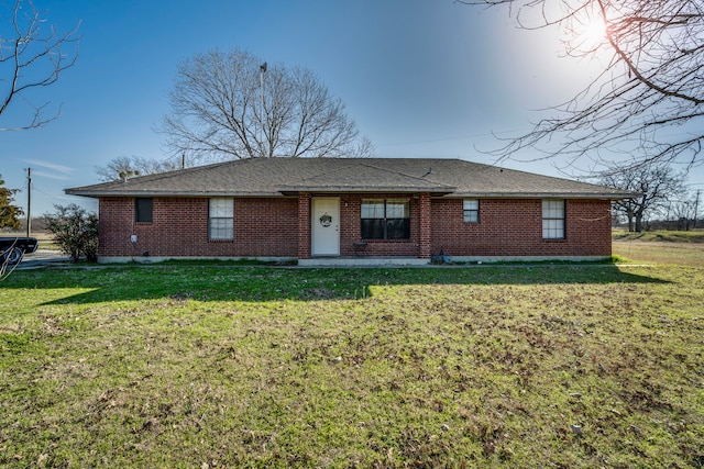 single story home featuring brick siding, roof with shingles, and a front yard