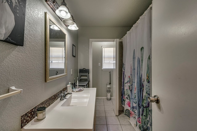 bathroom featuring curtained shower, tile patterned flooring, vanity, and a textured wall