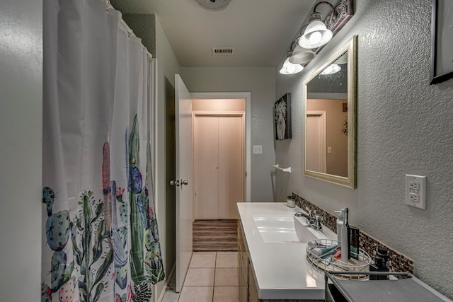 full bath featuring a textured wall, curtained shower, tile patterned flooring, vanity, and visible vents