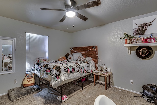 carpeted bedroom featuring ceiling fan, a textured wall, and baseboards