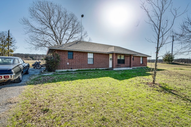 exterior space featuring brick siding, a lawn, gravel driveway, and a shingled roof