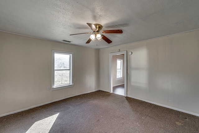 empty room with carpet, a healthy amount of sunlight, visible vents, and a textured ceiling