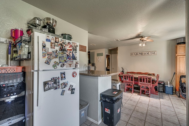 kitchen featuring freestanding refrigerator, ceiling fan, a textured ceiling, and light tile patterned floors