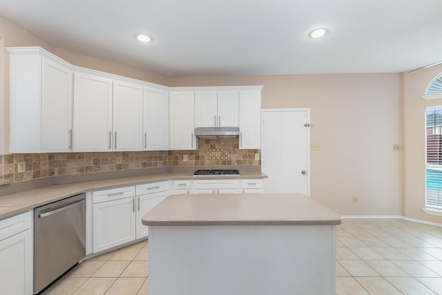 kitchen with light tile patterned floors, under cabinet range hood, a kitchen island, appliances with stainless steel finishes, and backsplash