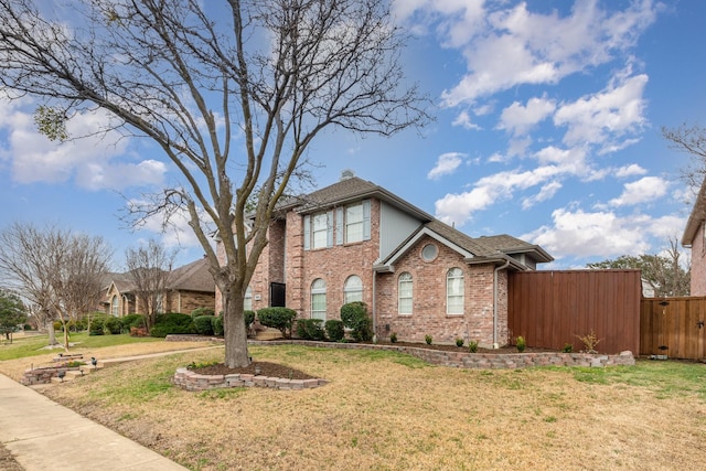 view of front of home with brick siding, fence, a chimney, and a front lawn