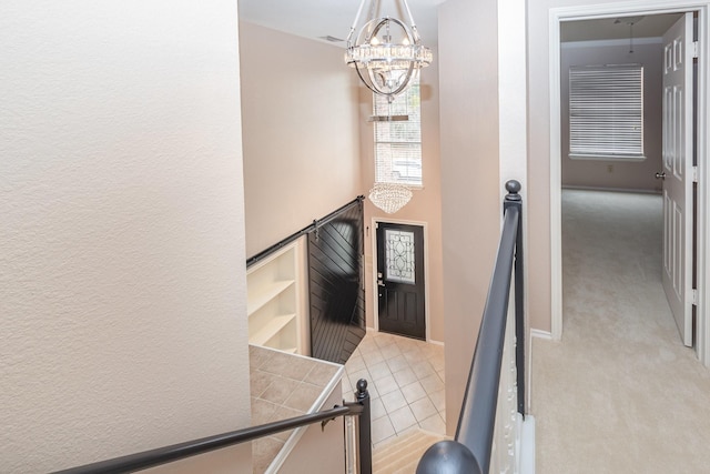 stairs featuring carpet floors, an inviting chandelier, tile patterned flooring, and baseboards