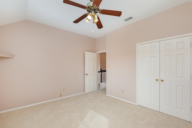 unfurnished bedroom featuring light carpet, visible vents, baseboards, vaulted ceiling, and a closet