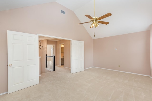 unfurnished room featuring light carpet, high vaulted ceiling, baseboards, and visible vents