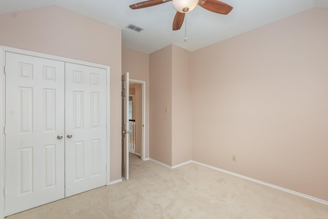 unfurnished bedroom featuring light carpet, visible vents, baseboards, vaulted ceiling, and a closet