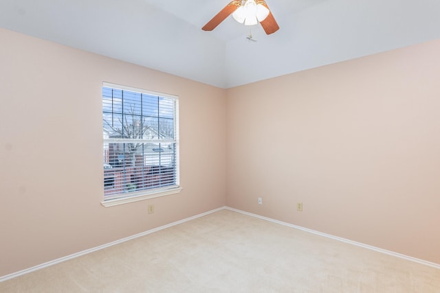 spare room featuring light carpet, ceiling fan, lofted ceiling, and baseboards