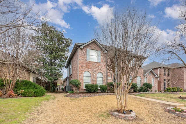 traditional-style home featuring a front yard, central AC unit, and brick siding