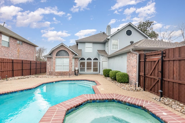 view of pool with a pool with connected hot tub, fence, and a gate