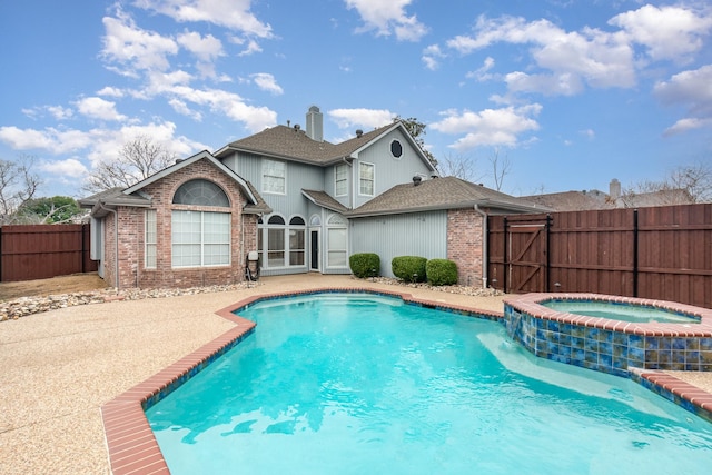 view of swimming pool with a pool with connected hot tub, a patio area, fence, and a gate