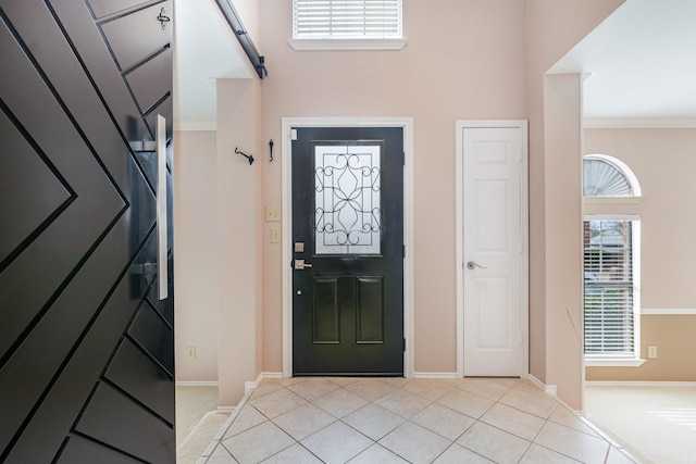 foyer entrance featuring light tile patterned flooring, crown molding, and baseboards