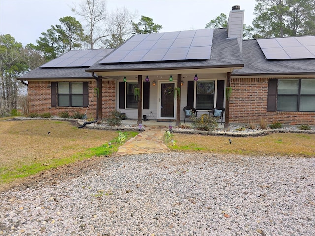 ranch-style house with covered porch, brick siding, a front lawn, and a chimney