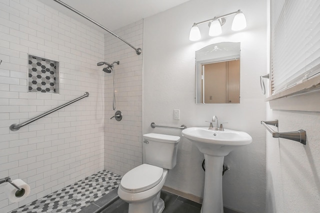 full bath featuring toilet, a sink, and tiled shower