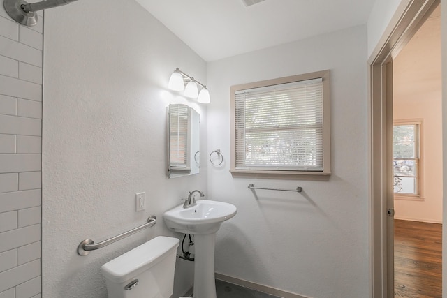 bathroom with a healthy amount of sunlight, toilet, and wood finished floors