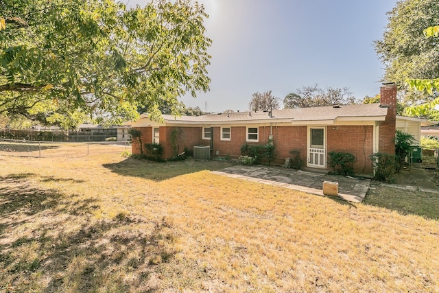 rear view of property with a lawn, fence, cooling unit, a patio area, and brick siding