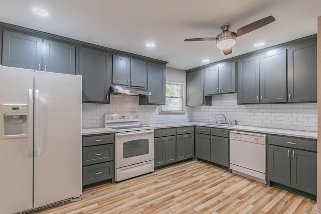 kitchen with light countertops, a sink, light wood-type flooring, white appliances, and under cabinet range hood