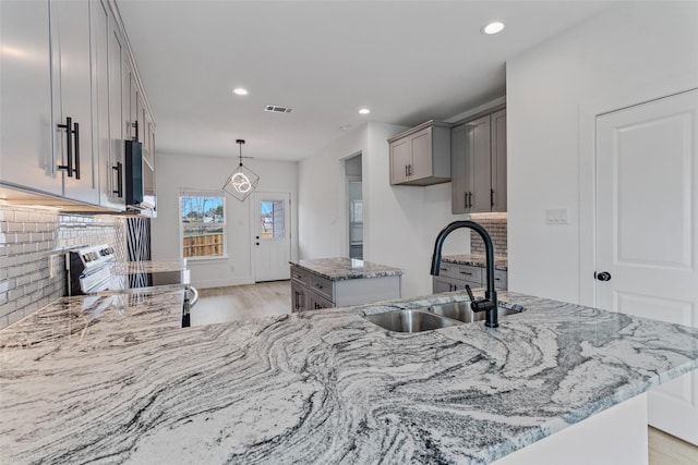 kitchen featuring light wood-style flooring, a sink, visible vents, appliances with stainless steel finishes, and light stone countertops