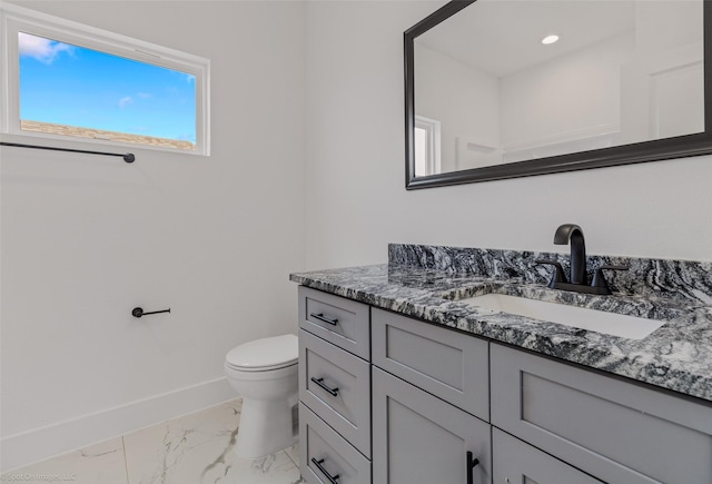 bathroom featuring toilet, marble finish floor, baseboards, and vanity