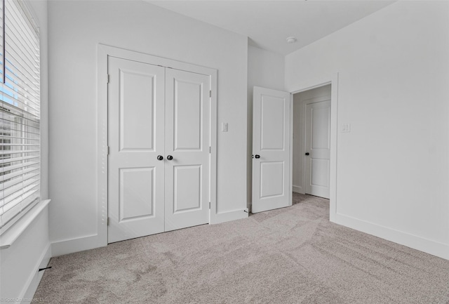 unfurnished bedroom with carpet floors, a closet, and baseboards