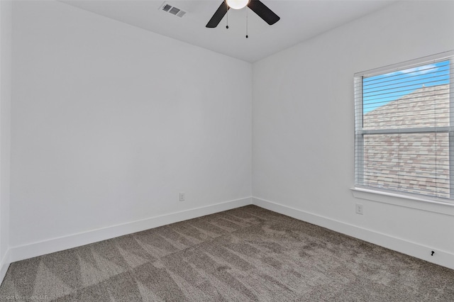 empty room featuring ceiling fan, dark colored carpet, visible vents, and baseboards